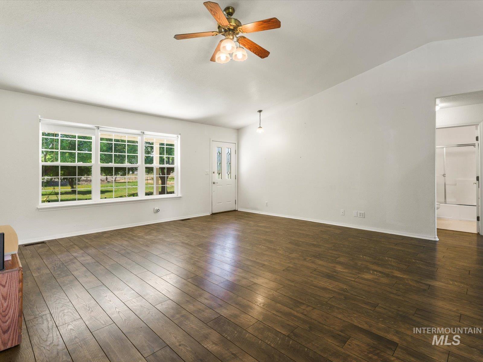 3540 Wills Road Emmett, ID 83617 - Photo 7 of 36 Spacious room featuring wood-finish flooring, a decorative entry door with glass inserts, and a multi-pane window overlooking a verdant exterior