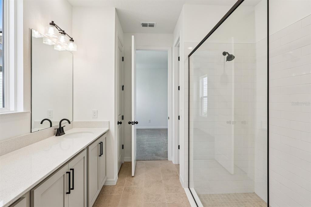 6673 Wake Street St. Cloud, FL 34771 - Photo 27 of 44 a bathroom with a double vanity sink a mirror and a shower