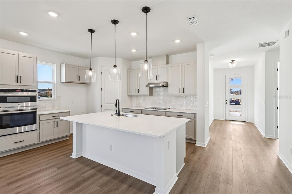 6673 Wake Street St. Cloud, FL 34771 - Photo 10 of 44 a large kitchen with stainless steel appliances kitchen island a large island a stove a refrigerator and a wooden floors