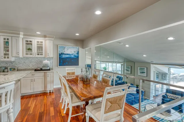 a kitchen with stainless steel appliances granite countertop a sink dishwasher a dining table and chairs with wooden floor