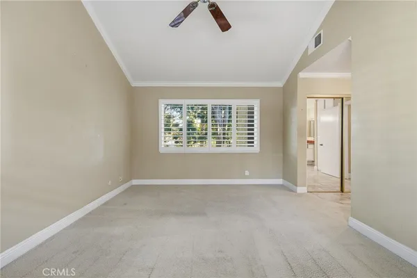 an empty room with ceiling fan and window
