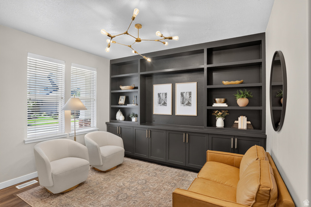 Built-in shelving with lower cabinetry, two windows with blinds, wood-finish flooring, and a modern ceiling fixture
