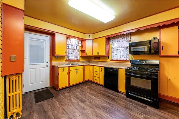 a kitchen with stainless steel appliances granite countertop a stove a sink and a refrigerator with wooden floors
