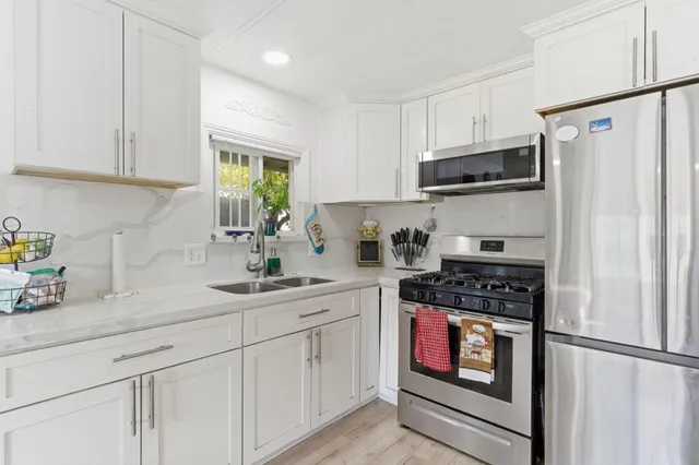 a kitchen with white cabinets sink and refrigerator