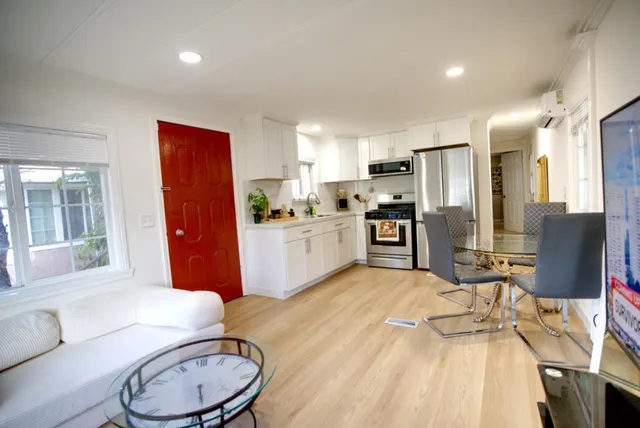 a kitchen with stainless steel appliances granite countertop a refrigerator a stove a sink a dining table and chairs with wooden floor