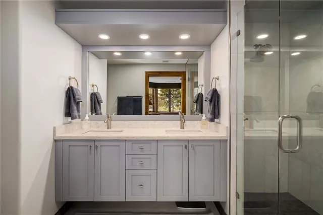 a bathroom with double vanity and a mirror