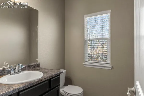 a bathroom with a granite countertop toilet sink and mirror