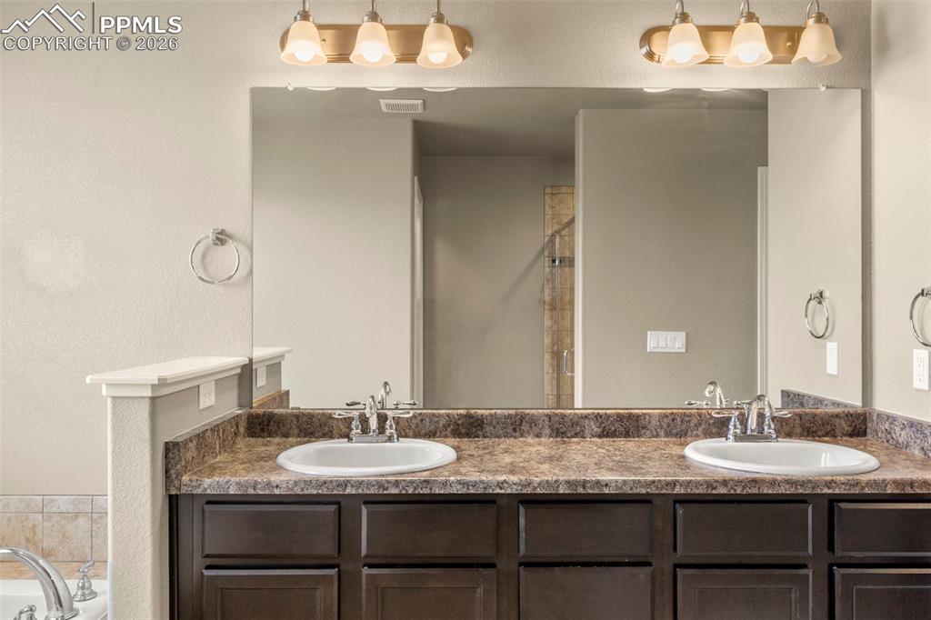 6105 Fiddle Way Colorado Springs, CO 80925 - Photo 18 of 40 a bathroom with a granite countertop sink and a mirror