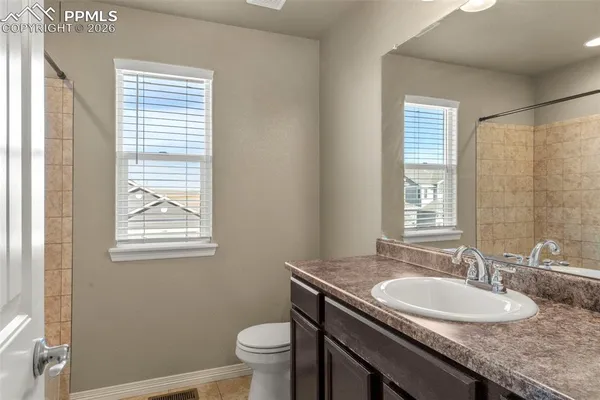 a bathroom with a granite countertop sink a toilet and a window