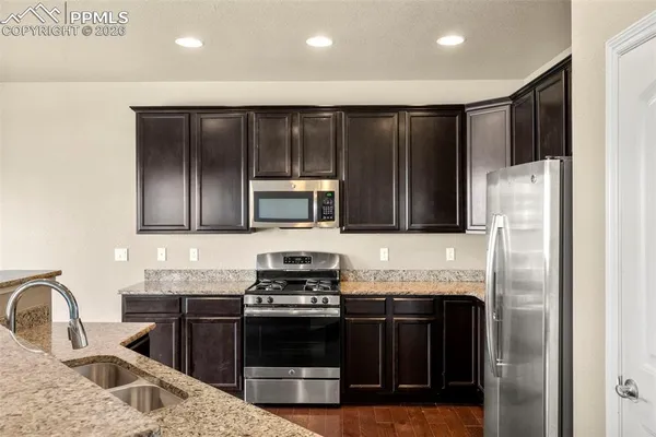 a kitchen with stainless steel appliances granite countertop a refrigerator stove and sink
