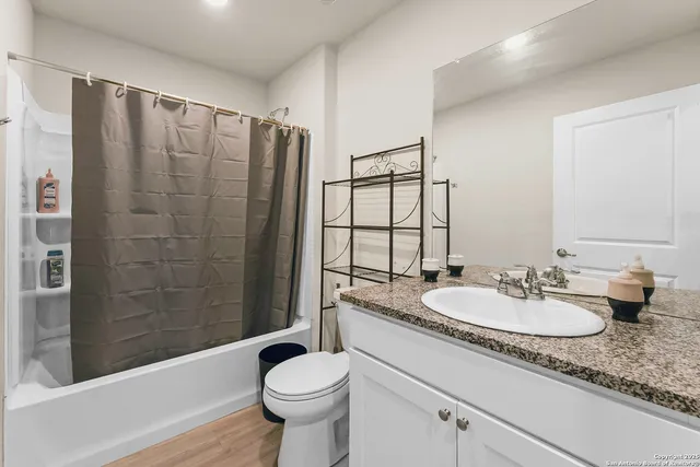 a bathroom with a sink a toilet a mirror and shower