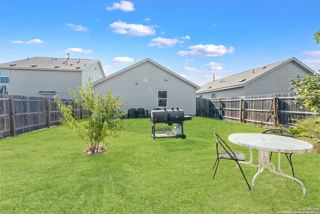 a view of a chair and table in backyard of the house