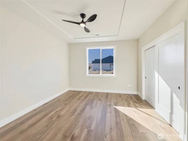a view of empty room with wooden floor and fan