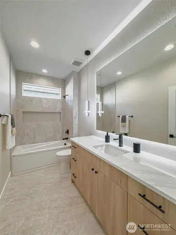 a bathroom with a tub sink double vanity and mirror
