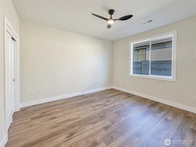 a view of empty room with wooden floor and fan