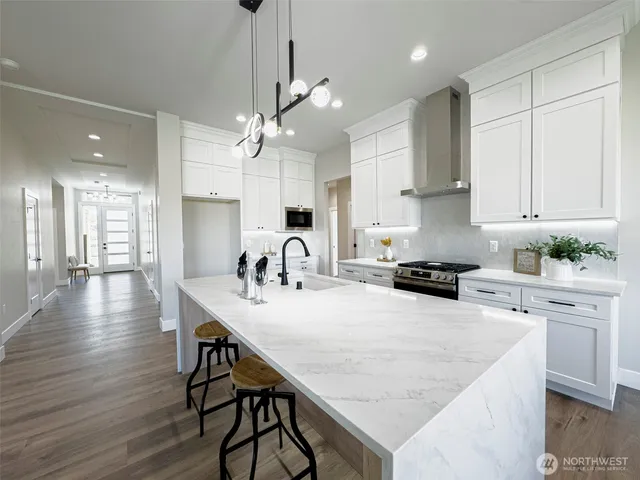 a kitchen with stainless steel appliances granite countertop a table chairs stove and white cabinets