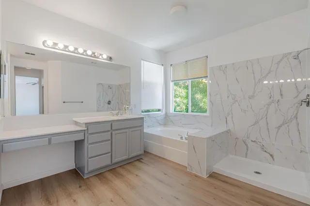 a bathroom with a double vanity sink a large mirror and a bathtub