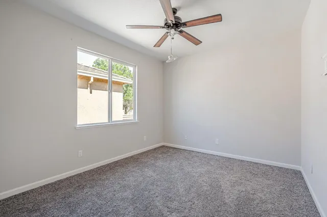an empty room with a window and a fan