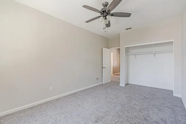 an empty room with a ceiling fan and carpet