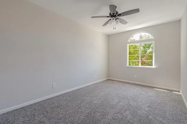 an empty room with windows and fan