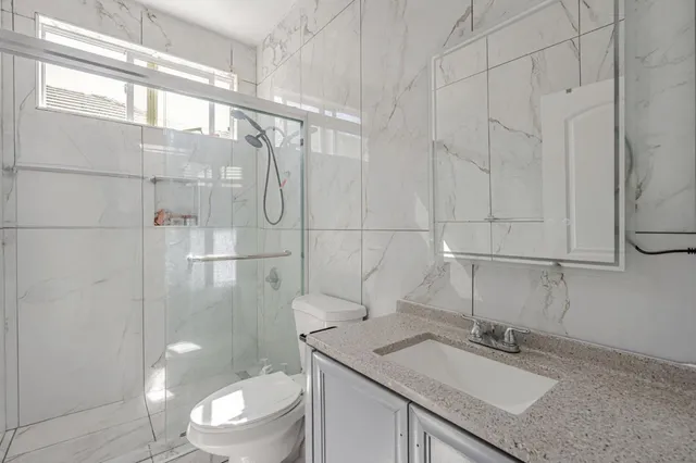a bathroom with a granite countertop sink a toilet and shower