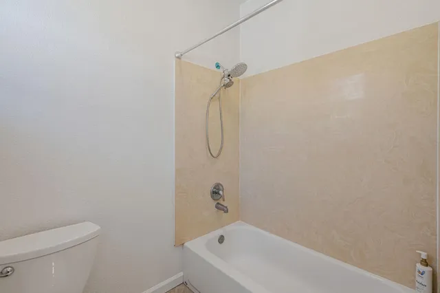 a bathroom with a granite countertop toilet and a bath tub