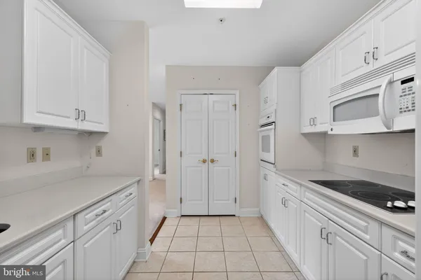 a kitchen with white cabinets and appliances