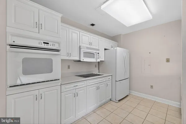 a kitchen with white cabinets and white appliances