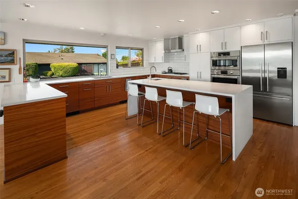 a kitchen with stainless steel appliances kitchen island granite countertop a table chairs sink and cabinets