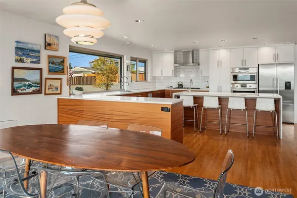 a living room with stainless steel appliances dining table chairs and wooden floor