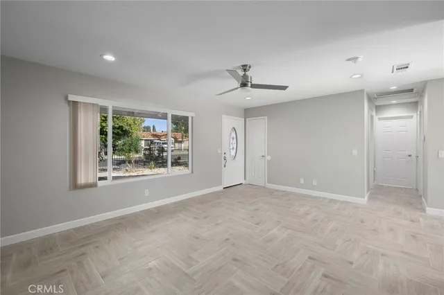 a view of an empty room with window and wooden floor
