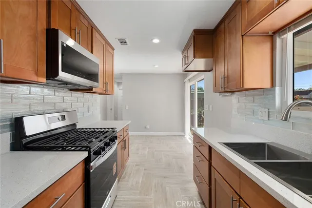 a kitchen with stainless steel appliances granite countertop a stove a sink a refrigerator and a microwave