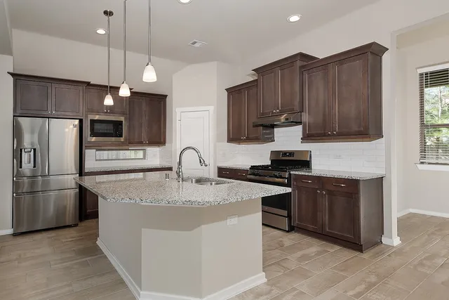 a kitchen with kitchen island granite countertop stainless steel appliances a sink stove and refrigerator