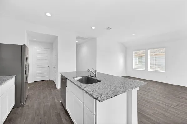 a kitchen with granite countertop kitchen island stainless steel appliances a sink and a refrigerator