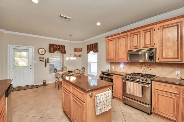 a kitchen with stainless steel appliances granite countertop a stove top oven a refrigerator a sink and dishwasher with white cabinets