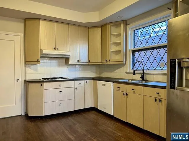 a kitchen with stainless steel appliances granite countertop a sink and cabinets with wooden floor