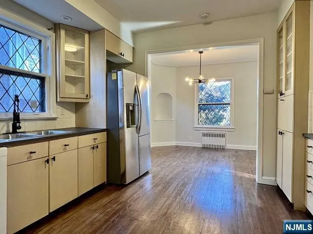 a kitchen with stainless steel appliances granite countertop a refrigerator a sink and white cabinets with wooden floor