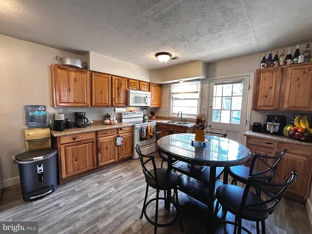 a kitchen with a dining table chairs and wooden floor