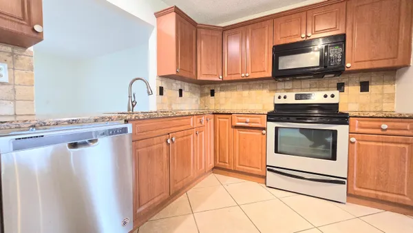 a kitchen with stainless steel appliances granite countertop a refrigerator stove top oven a sink and dishwasher