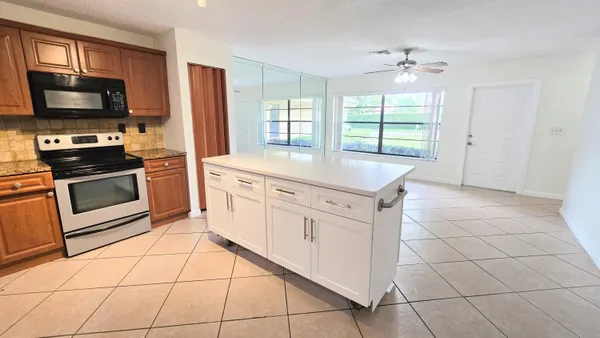 a kitchen with stainless steel appliances granite countertop a stove top oven a sink dishwasher and a refrigerator with wooden cabinets