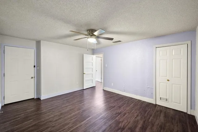 an empty room with wooden floor and ceiling fan