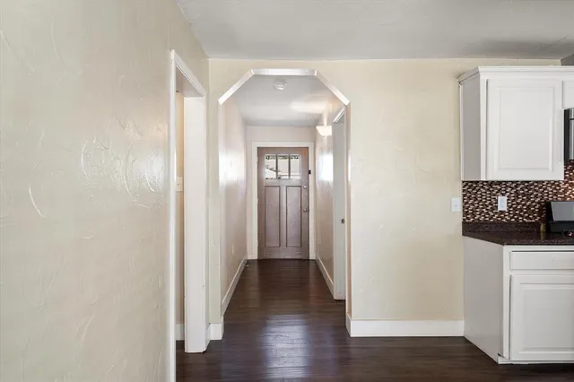 a kitchen with a counter top space a stove wooden floor cabinets and a window