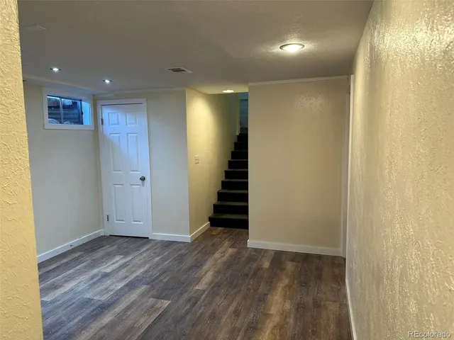 an empty room with wooden floor and stairs