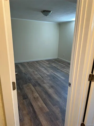 a view of an empty room with wooden floor and closet