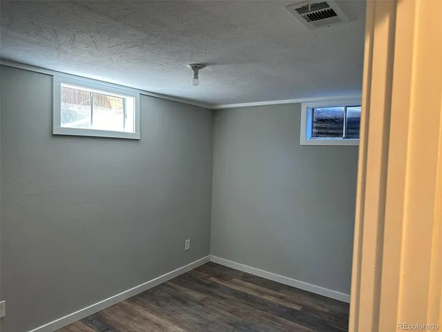 a view of an empty room with wooden floor and closet area