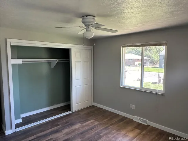an empty room with wooden floor closet and windows