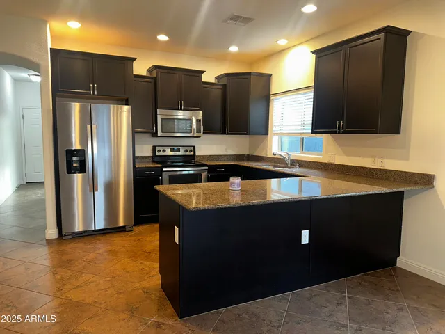 a kitchen with stainless steel appliances granite countertop a refrigerator and a sink