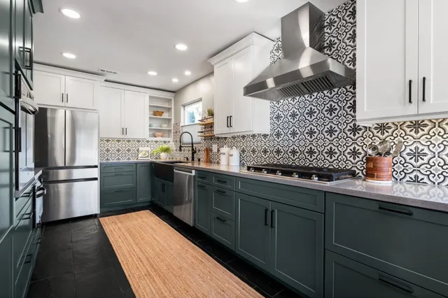 a kitchen with stainless steel appliances kitchen island granite countertop a refrigerator a sink dishwasher a stove and white cabinets with wooden floor