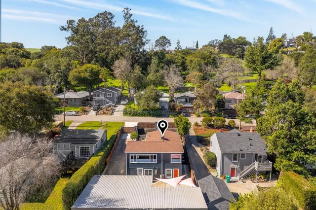 an aerial view of a house with swimming pool and large trees
