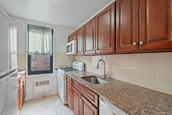 a kitchen with stainless steel appliances granite countertop a sink and dishwasher wooden cabinets with a granite countertops